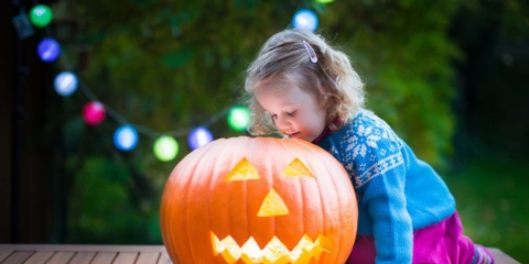 little girl playing with a jack-o-latern on halloween
