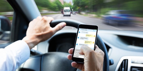 Man typing a text while driving