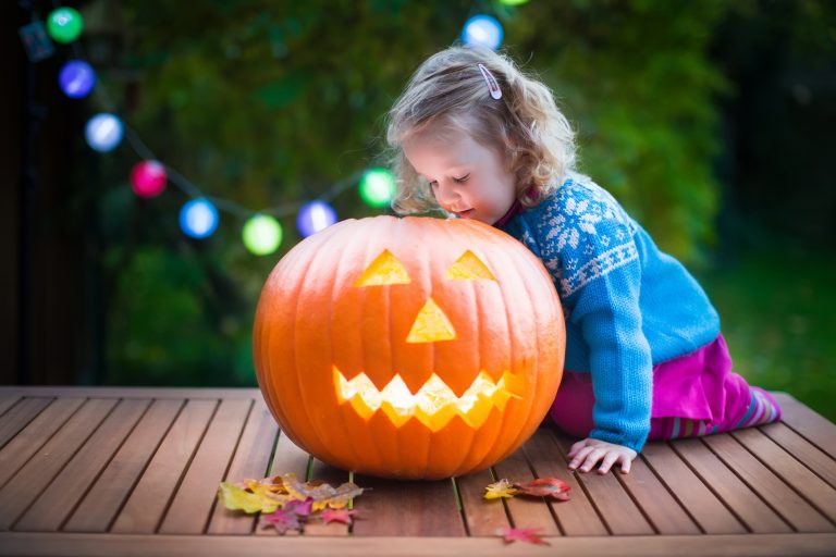 little girl playing with a jack-o-latern on halloween